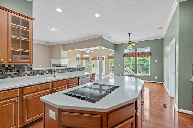 kitchen featuring ceiling fan, a sink, dishwasher, black electric stovetop, and brown cabinetry