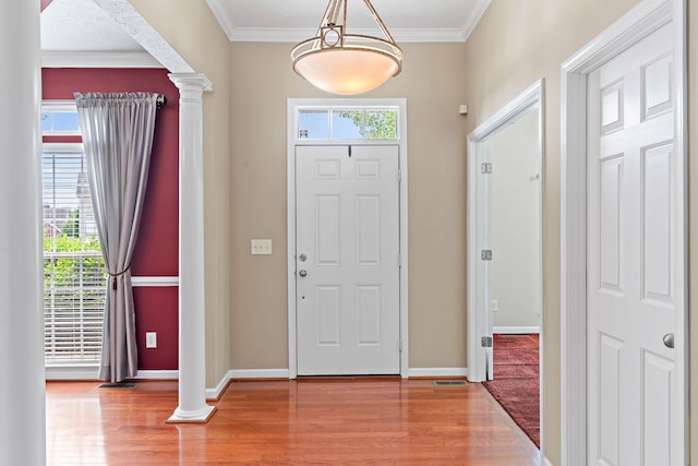 entryway featuring ornate columns, wood finished floors, crown molding, and baseboards