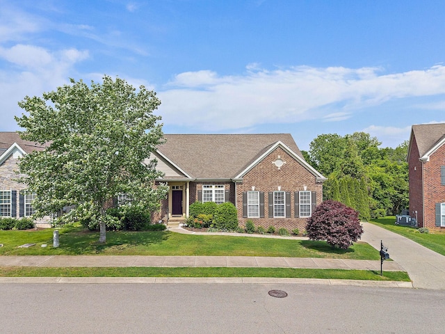 view of front of property featuring brick siding, a front lawn, and roof with shingles