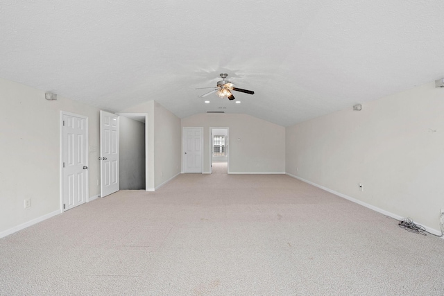 unfurnished living room featuring lofted ceiling, a ceiling fan, light carpet, and baseboards