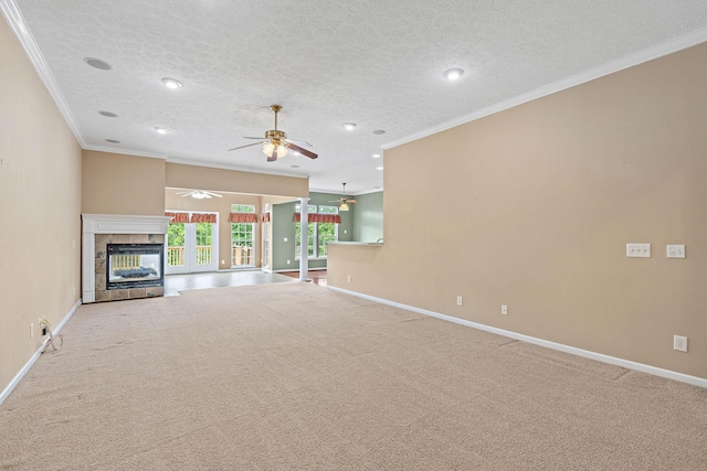 unfurnished living room featuring ornamental molding, a tiled fireplace, ceiling fan, baseboards, and carpet floors