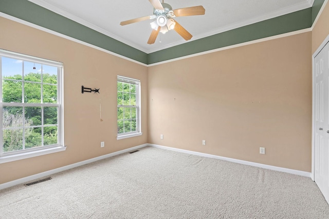 carpeted spare room featuring baseboards, ornamental molding, and a ceiling fan