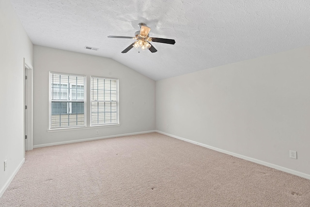 spare room featuring ceiling fan, lofted ceiling, a textured ceiling, carpet floors, and baseboards