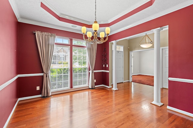 empty room featuring ornate columns, wood finished floors, a textured ceiling, a chandelier, and crown molding