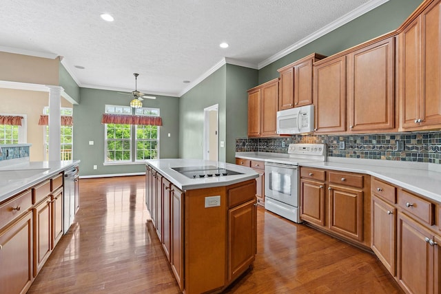 kitchen featuring white appliances, wood finished floors, a kitchen island, ceiling fan, and decorative backsplash