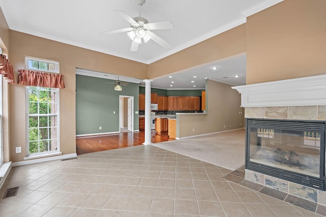 unfurnished living room featuring ornate columns, light tile patterned floors, ceiling fan, ornamental molding, and baseboards