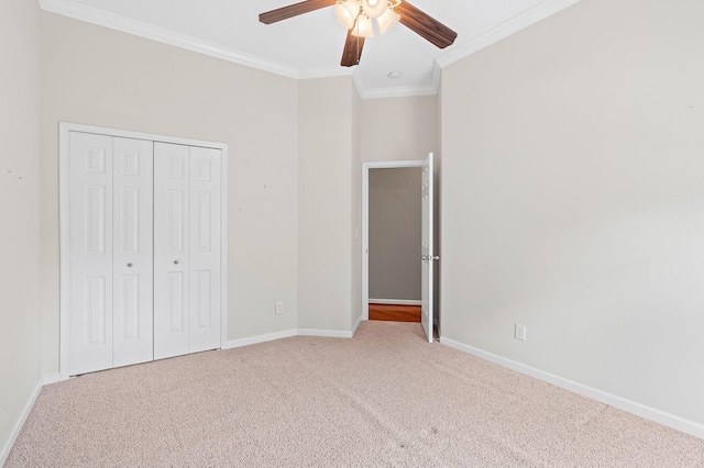 unfurnished bedroom with carpet, crown molding, baseboards, a closet, and ceiling fan