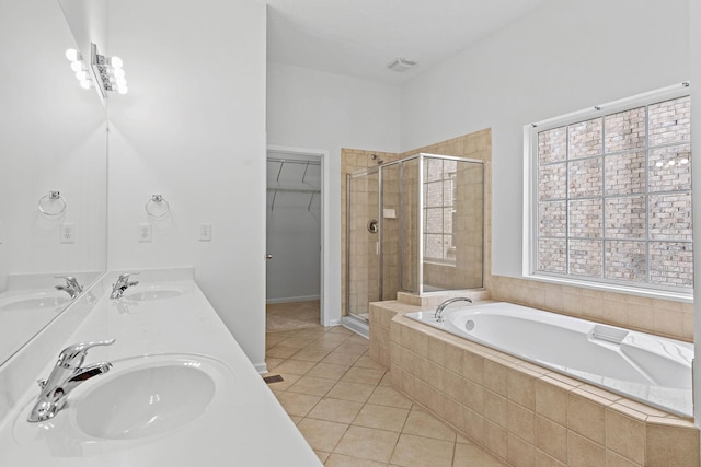 full bathroom featuring a stall shower, a bath, tile patterned flooring, double vanity, and a walk in closet