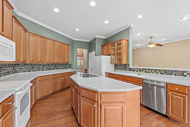 kitchen featuring white appliances, a sink, backsplash, a center island, and ceiling fan