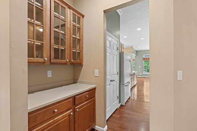 bar area featuring freestanding refrigerator, a textured ceiling, dark wood-style flooring, recessed lighting, and baseboards
