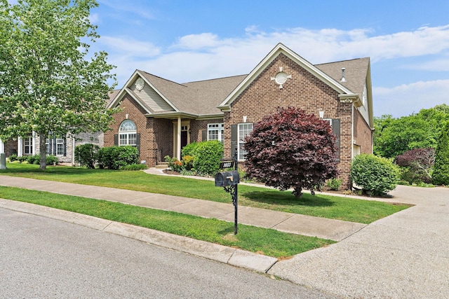 view of front of house featuring brick siding, a front yard, and a shingled roof