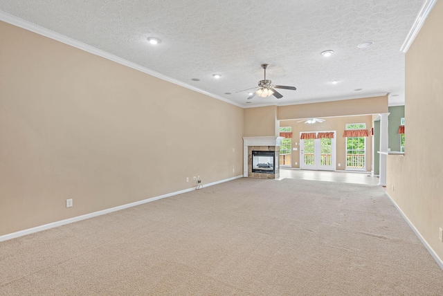 unfurnished living room featuring a fireplace, crown molding, a ceiling fan, carpet flooring, and baseboards