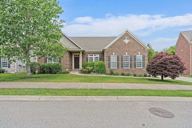 view of front of home with brick siding, a front lawn, and a shingled roof