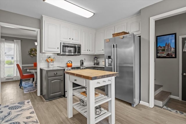 1209 Corlew Dr, Burns, TN 37029 - kitchen featuring appliances with stainless steel finishes, butcher block counters, white cabinetry, light wood-style flooring, and tasteful backsplash