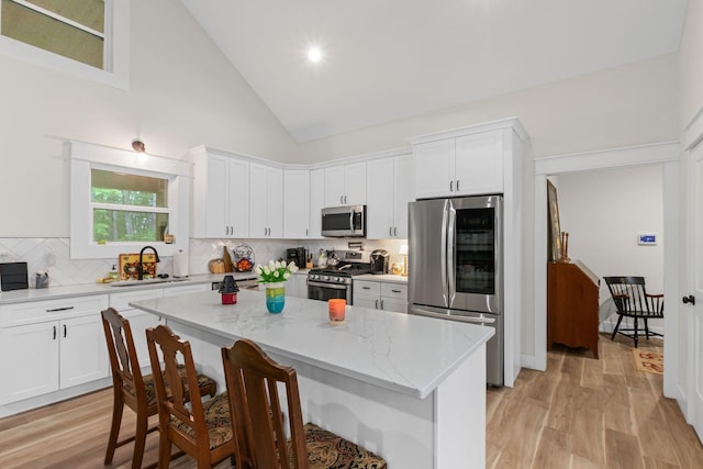 120 Destineys Way, Gruetli Laager, TN 37339 - kitchen featuring stainless steel appliances, light wood-style floors, a kitchen bar, tasteful backsplash, and high vaulted ceiling