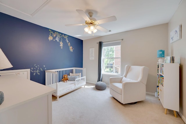 bedroom featuring a nursery area, light carpet, a ceiling fan, and baseboards
