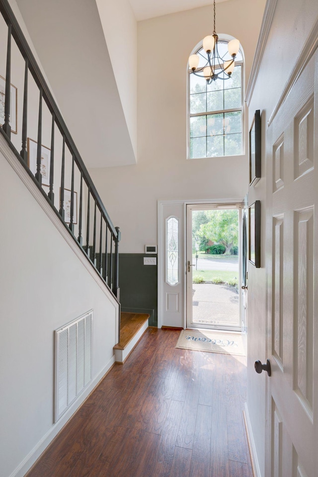 entrance foyer featuring a high ceiling, a chandelier, wood finished floors, stairway, and baseboards