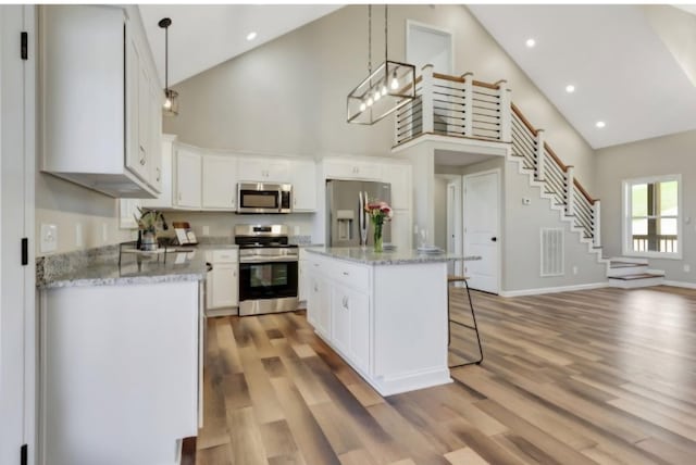 2582 Gap Rd, Altamont, TN 37301 - kitchen with appliances with stainless steel finishes, high vaulted ceiling, a breakfast bar area, light wood-type flooring, and white cabinets