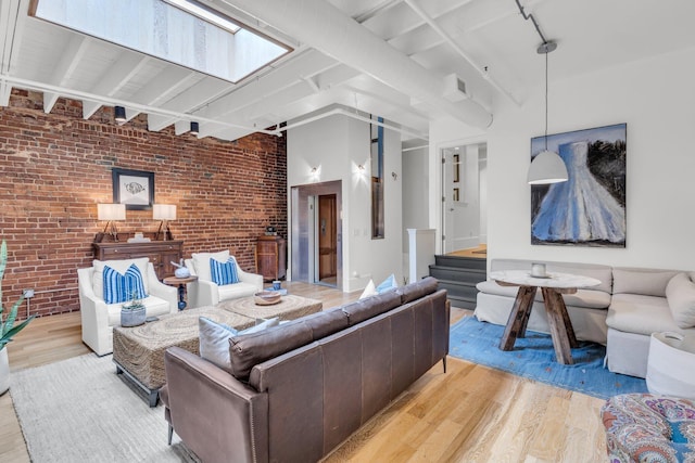 55 E Main St # 208, Chattanooga, TN 37408 - living room featuring brick wall, wood finished floors, track lighting, beam ceiling, and stairway