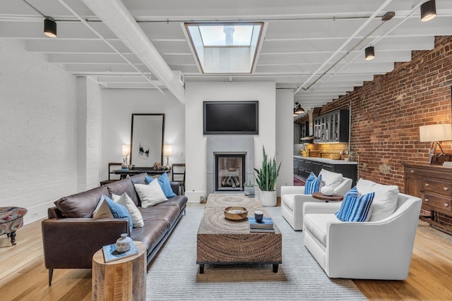 55 E Main St # 208, Chattanooga, TN 37408 - living area with brick wall, light wood-style flooring, and a glass covered fireplace