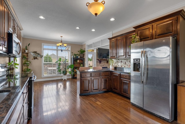 1607 Edgewater Ln, Clarksville, TN 37043 - kitchen featuring appliances with stainless steel finishes, a chandelier, a peninsula, dark wood-style flooring, and backsplash
