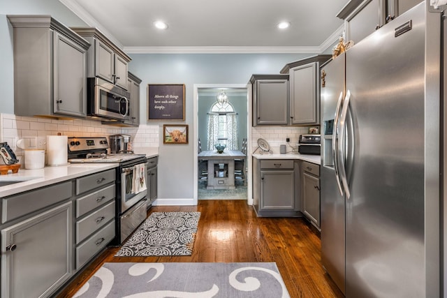kitchen featuring stainless steel appliances, gray cabinets, dark wood finished floors, tasteful backsplash, and ornamental molding