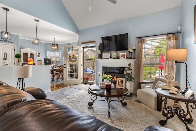 living room featuring vaulted ceiling, ceiling fan, wood finished floors, a glass covered fireplace, and crown molding