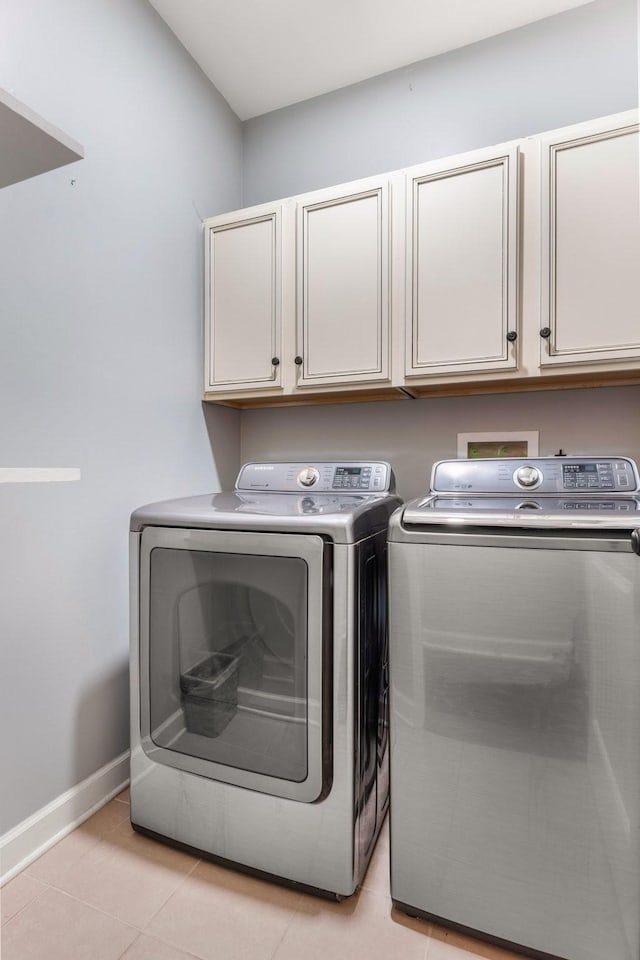 laundry area with washing machine and dryer, cabinet space, baseboards, and light tile patterned floors