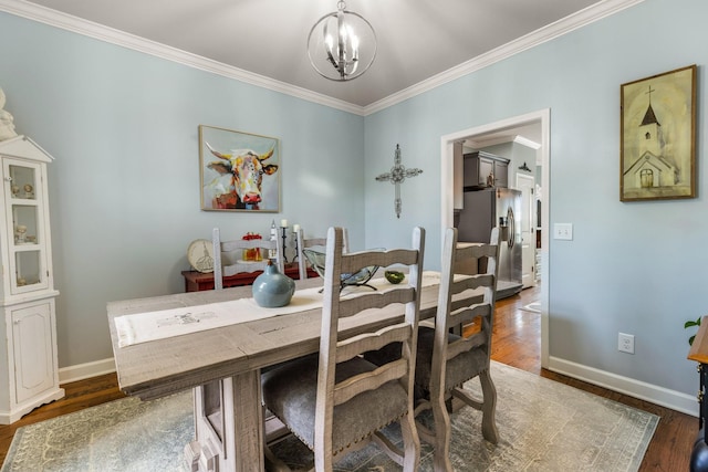 dining space featuring a chandelier, ornamental molding, wood finished floors, and baseboards