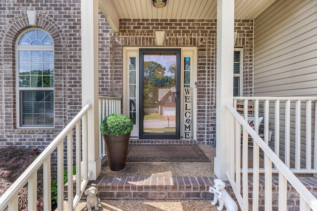 view of exterior entry featuring brick siding and a porch