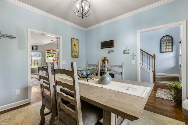 dining space featuring a chandelier, ornamental molding, baseboards, wood finished floors, and stairs