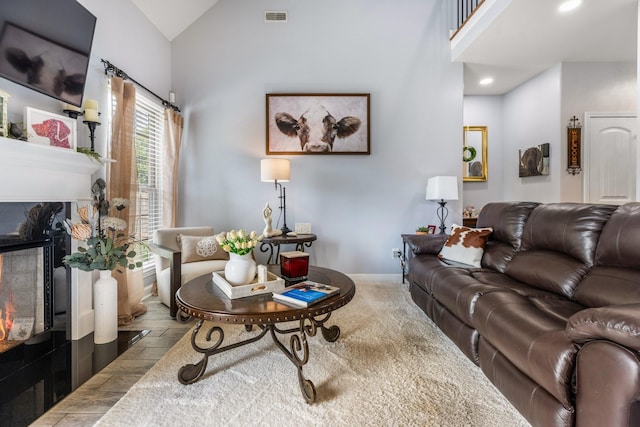 living area featuring a high end fireplace, recessed lighting, baseboards, and high vaulted ceiling
