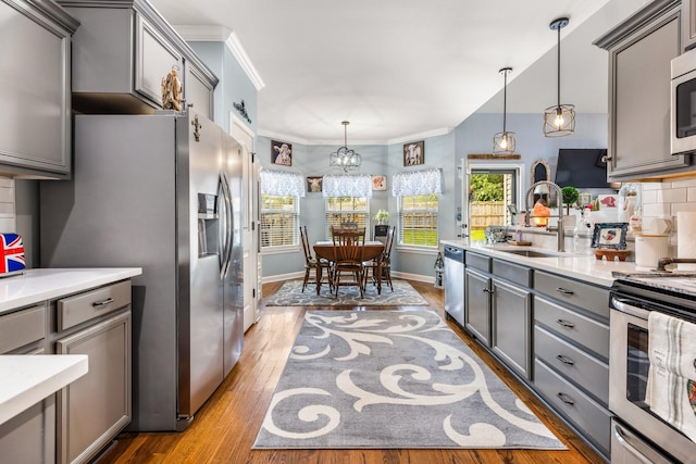 kitchen featuring gray cabinetry, appliances with stainless steel finishes, light wood-style floors, a sink, and crown molding