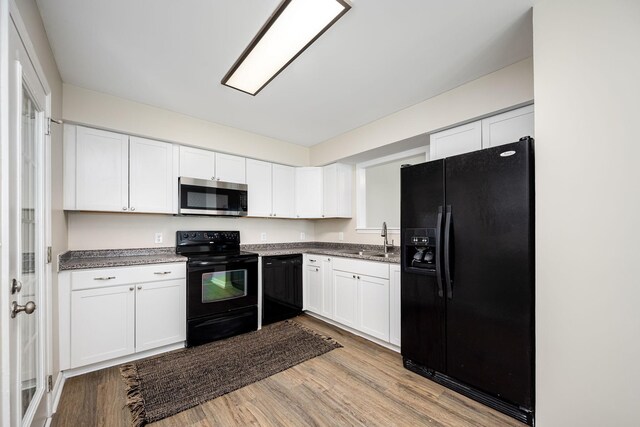 205 Blue Lake Dr, Tullahoma, TN 37388 - kitchen featuring black appliances, white cabinetry, light wood-type flooring, a sink, and dark countertops