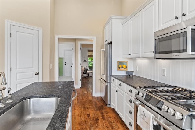 4145 Trinity Rd, Franklin, TN 37067 - kitchen with stainless steel appliances, a sink, white cabinetry, dark wood-style floors, and dark stone counters