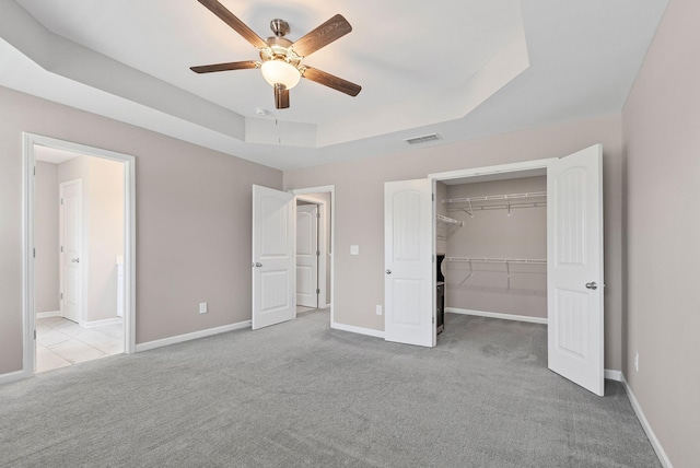 215 Ruth Way, Spring Hill, TN 37174 - unfurnished bedroom featuring carpet, a tray ceiling, a walk in closet, baseboards, and a ceiling fan