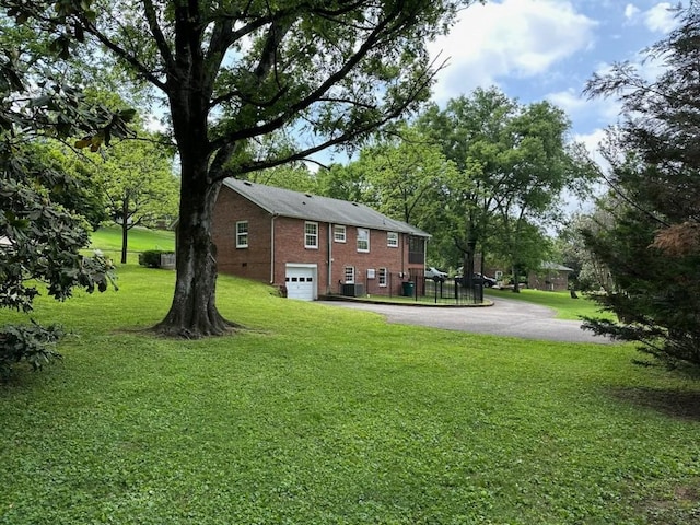108 Sunset Dr, Pulaski, TN 38478 - view of green lawn featuring asphalt driveway, an attached garage, and central AC unit
