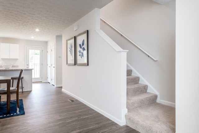 foyer entrance with stairway, dark wood-type flooring, baseboards, recessed lighting, and a textured ceiling