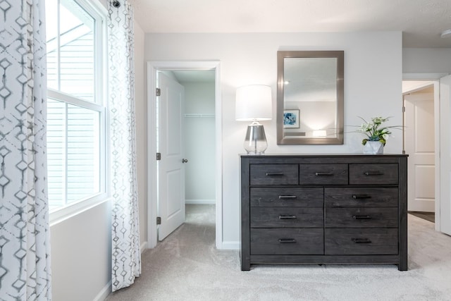 bedroom featuring light colored carpet, baseboards, and a spacious closet