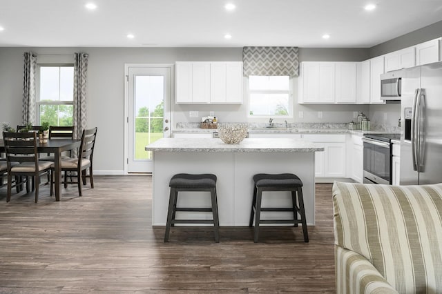 kitchen with appliances with stainless steel finishes, a center island, recessed lighting, a kitchen bar, and white cabinetry