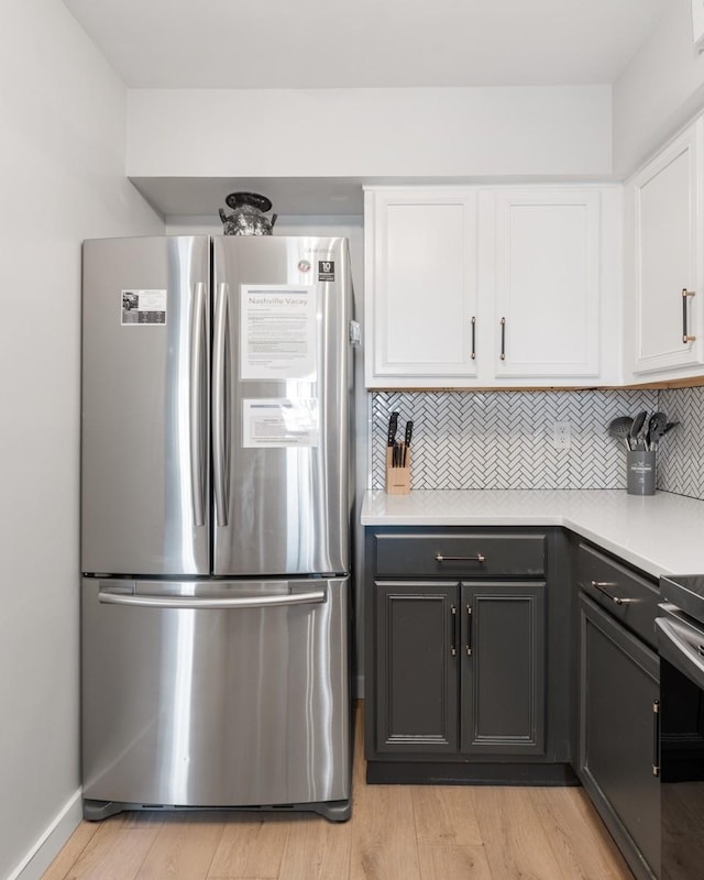 kitchen featuring appliances with stainless steel finishes, white cabinets, light countertops, decorative backsplash, and light wood-style floors