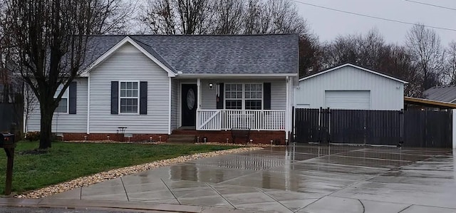 view of front of home with covered porch, driveway, a detached garage, and roof with shingles