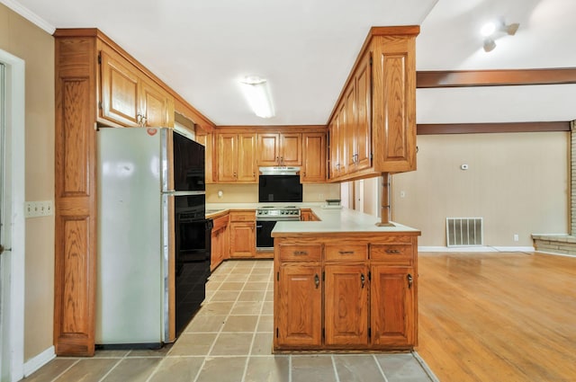 1033 Pine Valley Rd, Kingston Springs, TN 37082 - kitchen with freestanding refrigerator, stainless steel electric stove, light countertops, brown cabinetry, and under cabinet range hood