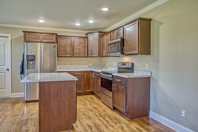1570 Clemmons Rd, Cookeville, TN 38501 - kitchen with appliances with stainless steel finishes, a kitchen island, crown molding, baseboards, and light wood-type flooring