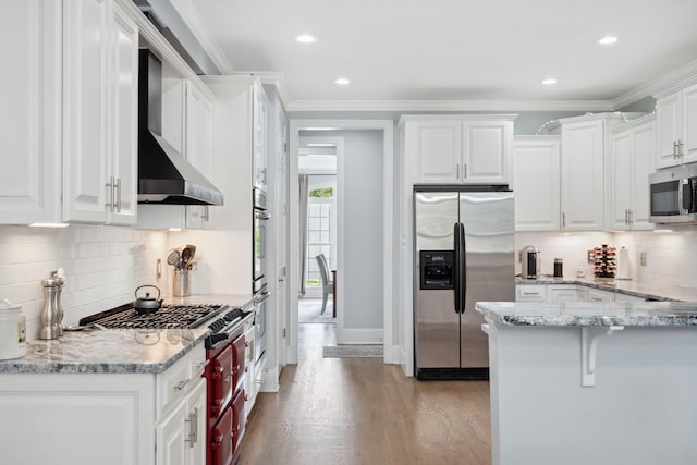 9702 Amethyst Ln, Brentwood, TN 37027 - kitchen with stainless steel appliances, wall chimney range hood, decorative backsplash, white cabinets, and light wood-style floors
