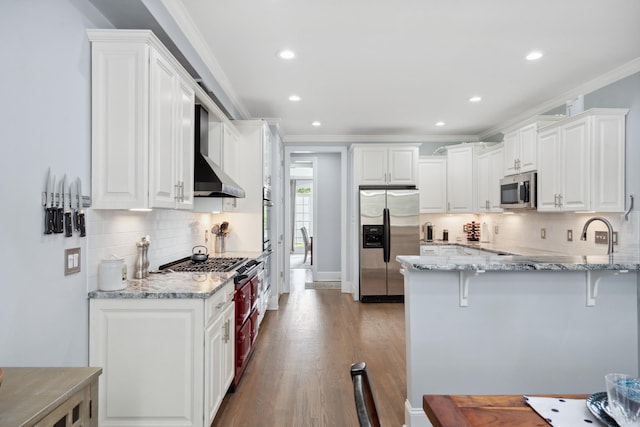 9702 Amethyst Ln, Brentwood, TN 37027 - kitchen featuring stainless steel appliances, wall chimney range hood, a peninsula, crown molding, and light stone countertops