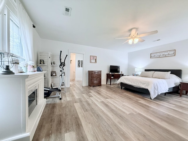 540 Grindstone Hollow Rd, Dickson, TN 37055 - bedroom featuring light wood-style floors, a glass covered fireplace, ceiling fan, and baseboards