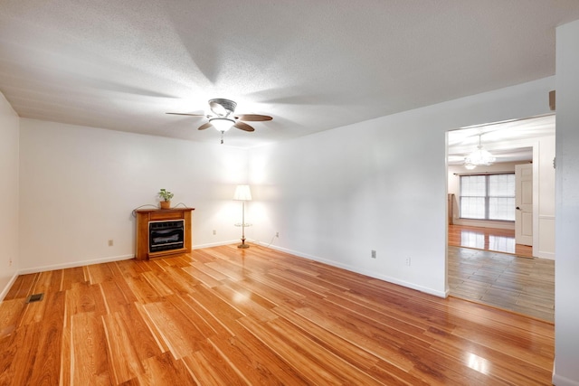 102 Hobbs Ridge Rd, Dunlap, TN 37327 - spare room featuring a ceiling fan, light wood-style floors, a fireplace, baseboards, and a textured ceiling