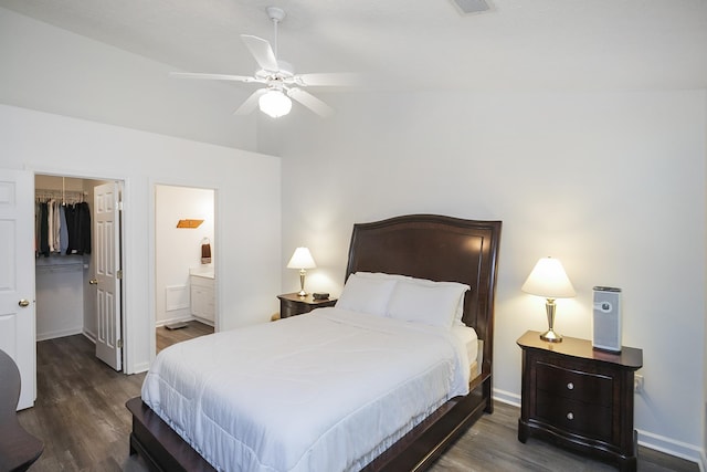 bedroom with a spacious closet, a closet, wood finished floors, and baseboards