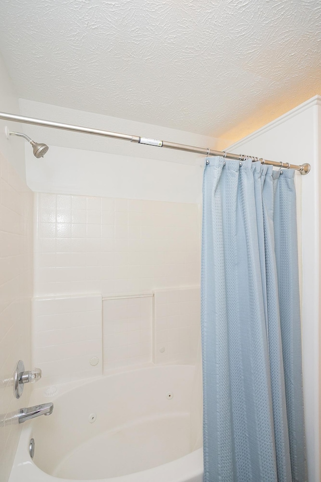 bathroom with shower / bathtub combination with curtain and a textured ceiling